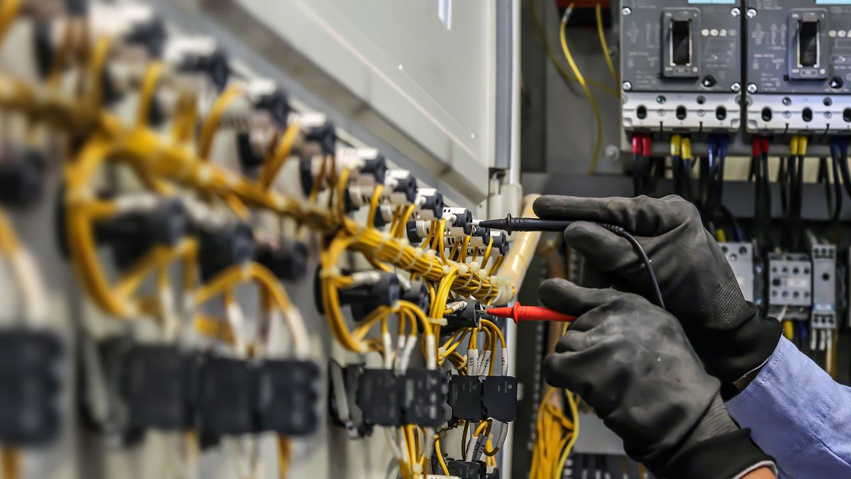 Técnico con guantes revisando conexiones en un tablero eléctrico