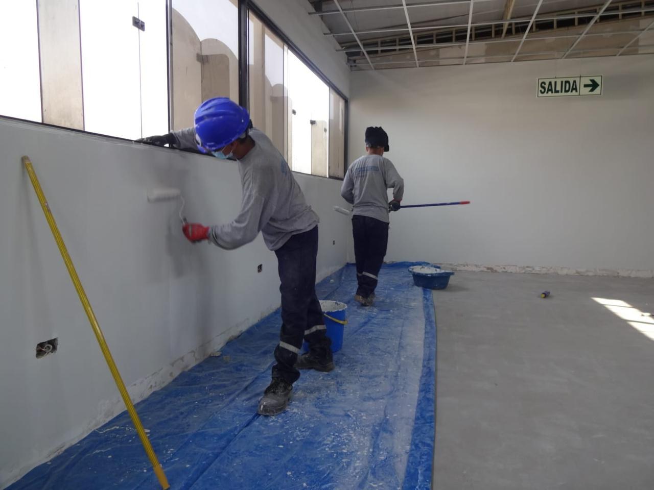 Pintores aplicando pintura blanca en un ambiente interior